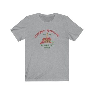 May include: Gray t-shirt with a red graphic of a basket of cherries and the text "CHERRY FESTIVAL 1926 1996 TRAVERSE CITY MICHIGAN".