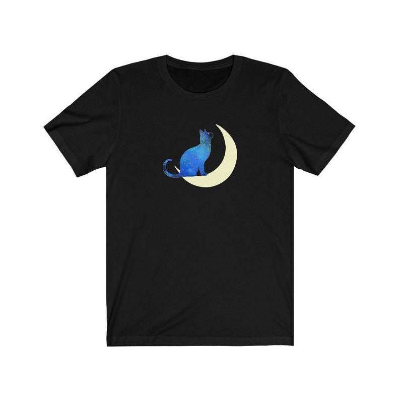 May include: A black t-shirt with a blue cat silhouette sitting on a crescent moon. The cat and moon are filled with a starry pattern.