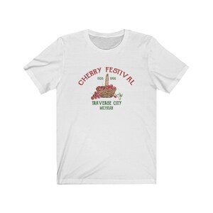 May include: White t-shirt with a red graphic of a basket of cherries and the text "CHERRY FESTIVAL 1926 1996 TRAVERSE CITY MICHIGAN".