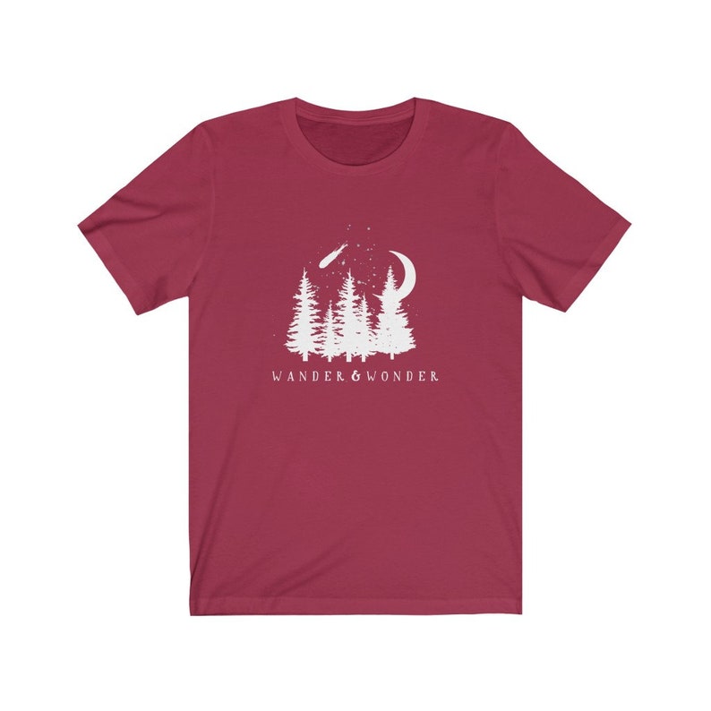 May include: A maroon t-shirt with a white graphic of a crescent moon, a shooting star, and a group of pine trees. The text "WANDER & WONDER" is printed below the graphic.