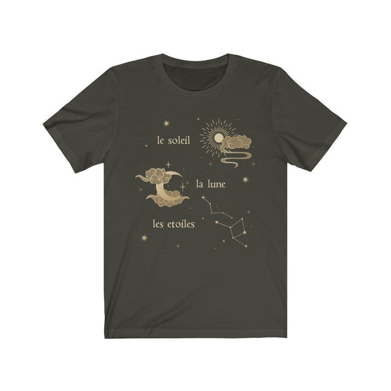 Puede incluir: Una camiseta verde oscuro con un dise&ntilde;o gr&aacute;fico dorado que presenta un sol, una luna y estrellas. El texto "le soleil", "la lune" y "les etoiles" est&aacute; impreso en dorado en la camiseta.