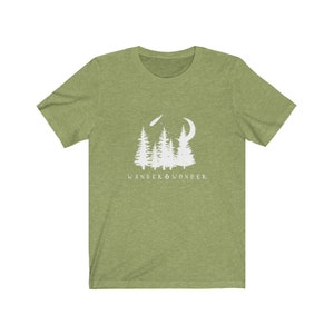 May include: A green short-sleeved t-shirt with a white graphic of a crescent moon, shooting star, and a group of pine trees. The text "WANDER & WONDER" is printed below the graphic.