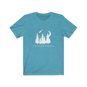 May include: A teal blue t-shirt with a white graphic of a forest scene with a crescent moon and a shooting star. The text "WANDER & WONDER" is printed below the graphic.