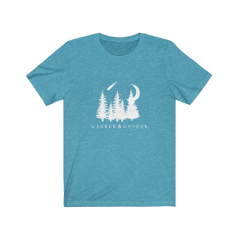 May include: A teal blue t-shirt with a white graphic of a forest scene with a crescent moon and a shooting star. The text "WANDER & WONDER" is printed below the graphic.