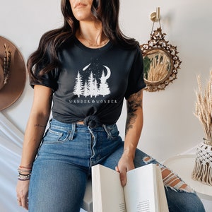 May include: A black t-shirt with a white graphic of trees, a crescent moon, and a shooting star. The text "WANDER & WONDER" is printed below the graphic.