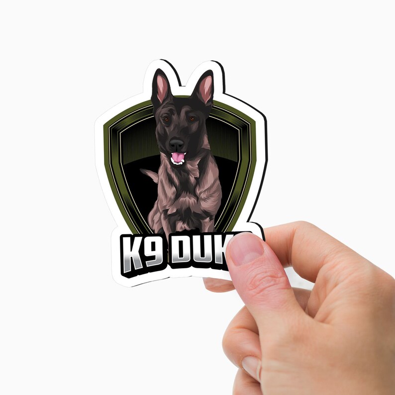 May include: A black and brown dog with a green shield behind it. The shield has a gold border and the text "K9 DUKE" is below the dog.