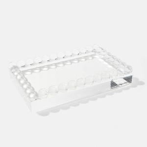 May include: A clear acrylic tray with a rectangular shape. The edges are lined with a row of clear, spherical beads. The tray has a smooth, transparent surface and a small, rectangular base.