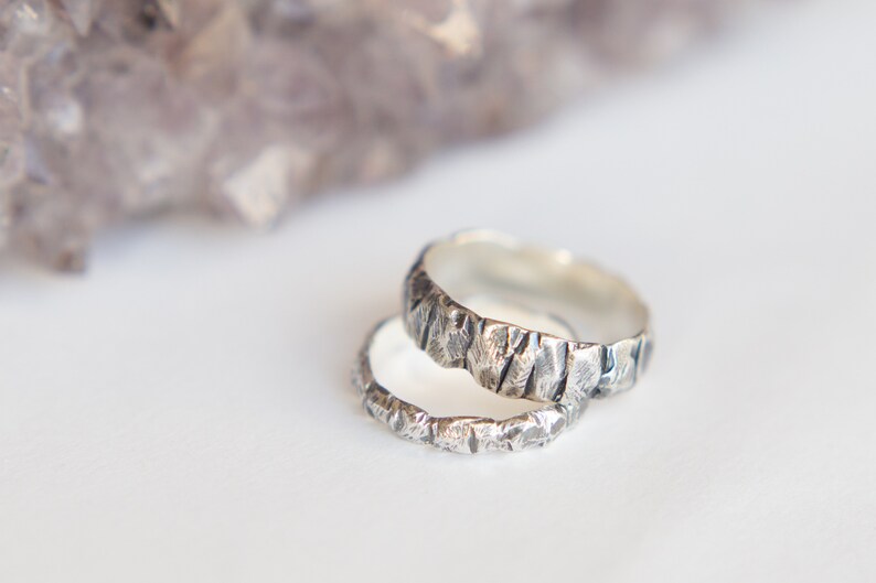 May include: Two silver rings with a textured, hammered finish. The rings are stacked on top of each other.