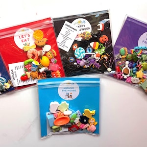 May include: Five clear plastic bags containing assorted miniature resin charms. The bags are labeled Let's Ready, Let's Eat, Happy Halloween, Pony Friends, and A Day at the Park. Each bag holds colorful, small-scale figures including food, animals, and holiday items.