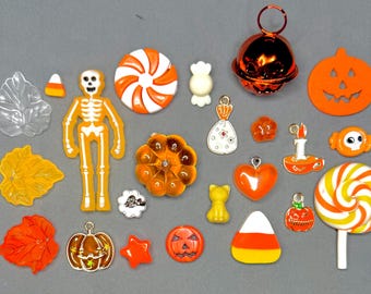 May include: A selection of Halloween-themed charms and embellishments in various shapes and colours. Includes pumpkins, a skeleton, candy corn, leaves, a bell, and a lollipop. Ideal for crafting or jewellery making.