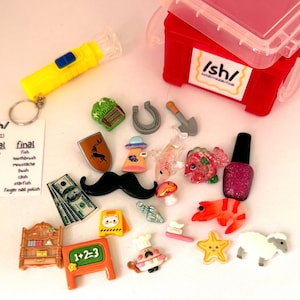 May include: A collection of miniature charms and trinkets including a red storage box labeled /sh/, a yellow flashlight, a shield with a deer, a mustache, play money, a chalkboard with 1+2=3, a shelf, a sheep, a shrimp, a starfish, and a nail polish.