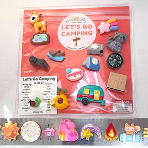 May include: A set of Let's Go Camping themed mini objects in a clear plastic bag, including a deer, raccoon, tent, compass, and camper. A ruler at the bottom shows the items range from approximately 1 to 8 inches in length.