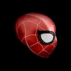 May include: A red leather mask with a black eye mask and white stitching. The mask is designed to look like a spider.
