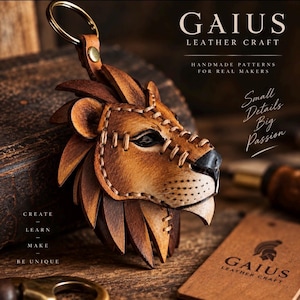 May include: A tan and brown leather keychain shaped like a lion head with visible stitching, a metal ring, and the text GAIUS LEATHER CRAFT, HANDMADE PATTERNS FOR REAL MAKERS, Small Details Big Passion, and CREATE LEARN MAKE BE UNIQUE.