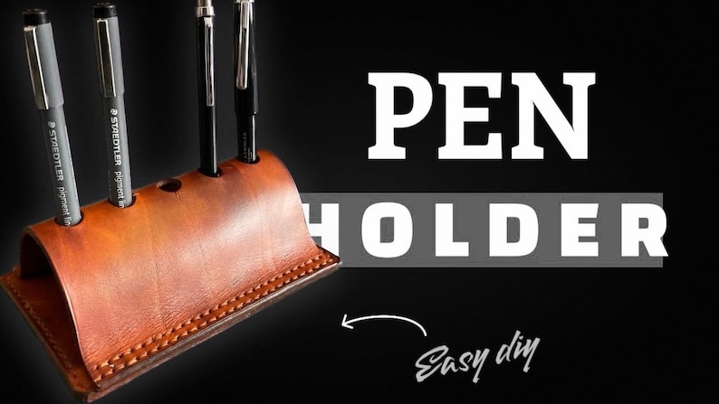 K&ouml;nnte beinhalten: Ein handgefertigter brauner Leder-Stifthalter mit drei Stiften. Der Stifthalter hat ein geschwungenes Design mit einem gen&auml;hten Rand. Die Worte "PEN HOLDER" sind in gro&szlig;en wei&szlig;en Buchstaben auf schwarzem Hintergrund zu sehen, mit "Easy diy" in Kursivschrift.