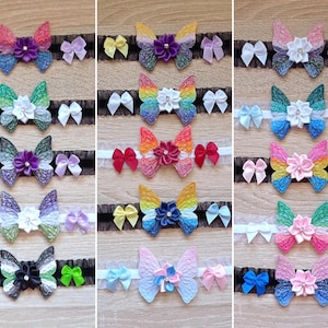 Puede incluir: Una colección de accesorios para el cabello con forma de mariposa en varios colores. Cada mariposa está adornada con una flor central y rodeada de pequeños lazos. Los accesorios están sujetos a cintas de encaje negro, ofreciendo un aspecto delicado.