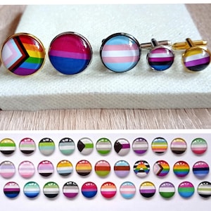 Può includere: Un set di 27 gemelli rotondi in vetro colorato che rappresentano diverse bandiere del pride. Le bandiere includono le bandiere transgender, lesbica, gay, bisessuale, pansessuale, asessuale e non binarie.