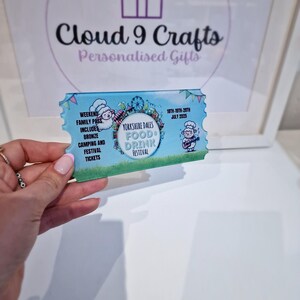 Pu&ograve; includere: Un biglietto blu e bianco per il Festival del Cibo e delle Bevande dello Yorkshire Dales, con una pecora dei cartoni animati e le date dal 18 al 20 luglio 2025.