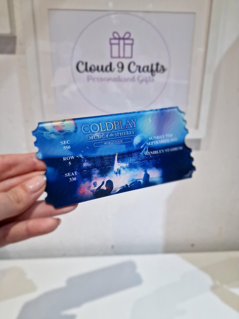 Pu&ograve; includere: Un biglietto blu e bianco per un concerto dei Coldplay. Il biglietto dice "Coldplay Music of the Spheres World Tour" e "Domenica 7 settembre 2023 Wembley Stadium". Il biglietto ha un numero di settore, fila e posto: Settore 550, Fila 5, Posto 330.