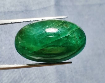 Pode incluir: Uma gema oval cabochão verde vibrante com uma superfície lisa e polida. A pedra tem uma aparência translúcida com inclusões internas visíveis.