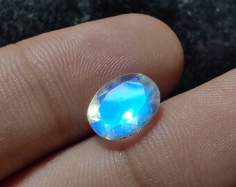 May include: Oval-shaped gemstone with a blue iridescent sheen. The gemstone is faceted and has a smooth, polished surface.