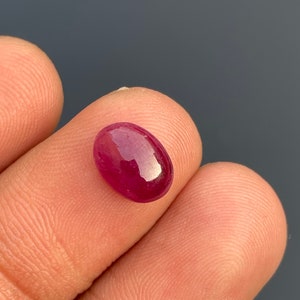 Pode incluir: Uma gema ovalada de cor vermelho-escuro com uma superfície lisa e polida.