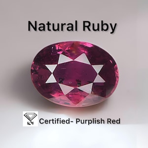 May include: An oval-shaped, purplish-red natural ruby gemstone. The gem has a star-like pattern within and is certified. The text "Natural Ruby" is above the gem, and "Certified- Purplish Red" is below.