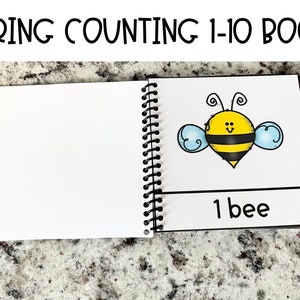 Könnte beinhalten: Ein Frühlings-Zählbuch mit einer Schwarzweißillustration einer Biene auf dem Cover. Der Text auf dem Cover lautet "SPRING COUNTING 1-10 BOOK". Das Buch hat eine Spiralbindung.