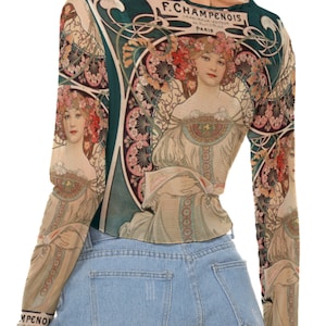 Peut inclure: Un chemisier à manches longues en tissu fin et transparent. Le chemisier présente un imprimé d'inspiration vintage d'une femme avec des fleurs dans les cheveux. L'impression comprend le texte "F. Champenois, Imprimeur-Editeur, Paris".