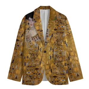 May include: A gold-toned blazer featuring a portrait of a woman and abstract patterns. The blazer has a single-button closure and a white interior lining. The design incorporates various shapes and colors, creating a unique artistic aesthetic.