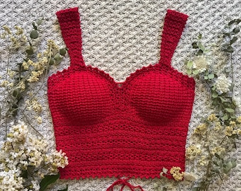 Puede incluir: Un top corto de crochet rojo con escote de corazón y tirantes ajustables. El top está hecho con un punto de crochet delicado y tiene un dobladillo festoneado.