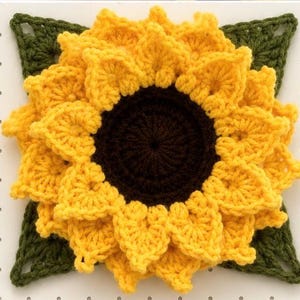 May include: A square crochet sunflower motif featuring a dark brown circular center surrounded by multiple layers of bright yellow textured petals, all layered over a dark green square base with openwork corner details for a dimensional effect.