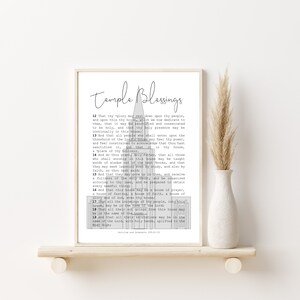 May include: Framed print with the words "Temple Blessings" in elegant script. The print features a stylized architectural illustration and text from Doctrine and Covenants 109:12-19. The print is displayed on a wooden shelf with a white vase and decorative dried grass.