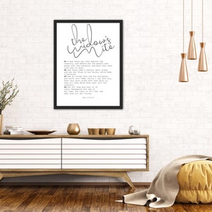 May include: Black and white framed print with the text "the widow's mite" and a bible verse from Mark 12:41-44. The print is hanging on a white brick wall above a wooden dresser.