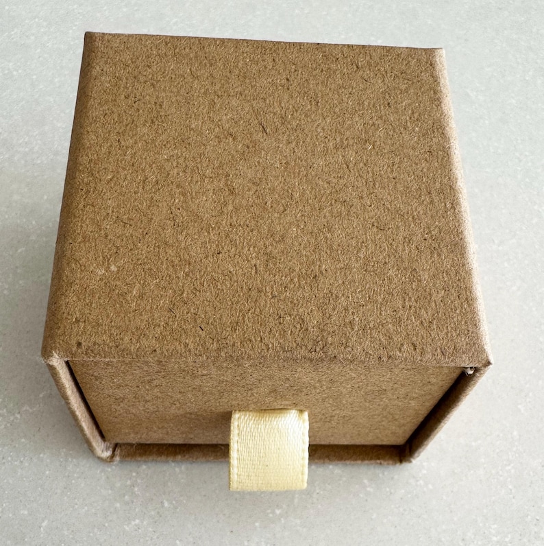 May include: A small, brown cardboard box with a pull-out drawer and a cream-colored fabric pull tab.