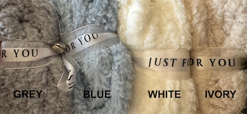 Puede incluir: Cuatro mantas esponjosas en gris, azul, blanco y marfil. Cada manta est&aacute; atada con una cinta que dice "Just for you".