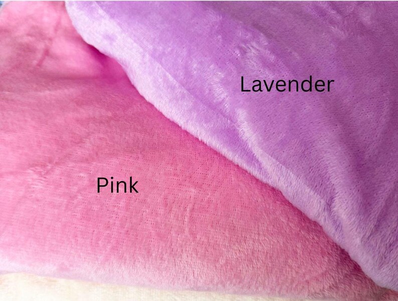 May include: Close-up of two plush fabrics, one pink and the other lavender. The pink fabric is labeled "Pink" and the lavender fabric is labeled "Lavender". The fabrics appear soft and fluffy.