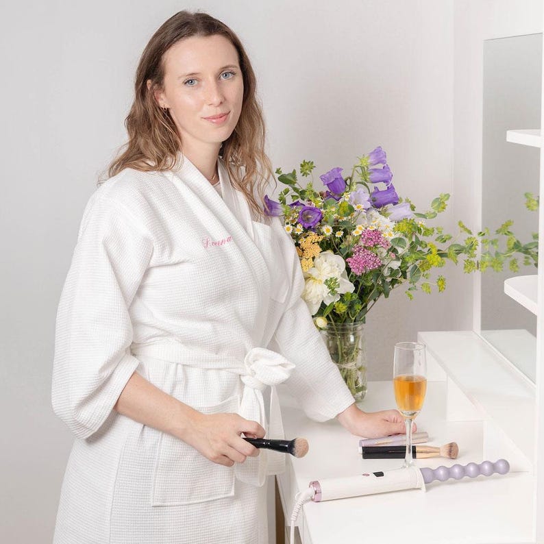 May include: A white ceramic mug with a colorful floral design. The mug features a variety of flowers in shades of pink, purple, and yellow. The handle is a solid white. The mug is likely for hot beverages.