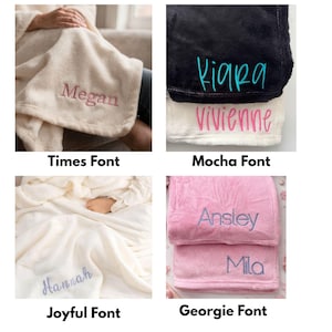 May include: Four plush blankets in different colors, each embroidered with a name in a unique font. The blankets are cream, black, white, and pink. The names embroidered are Megan, Kiara, Vivienne, Ansley, Mila, and Hannah. The fonts are Times, Mocha, Joyful, and Georgie.