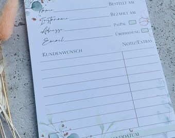 以下が含まれることがあります： 花柄と金色のアクセントが施された白いメモ帳。メモ帳には、書き込み用の線と、「No」、「名前」、「Instagram」、「住所」、「メールアドレス」、「お客様のご要望」、「注文日」、「お支払い日」、「PayPal」、「銀行振込」、「メモ/その他」、「価格」、「発送日」のセクションがあります。