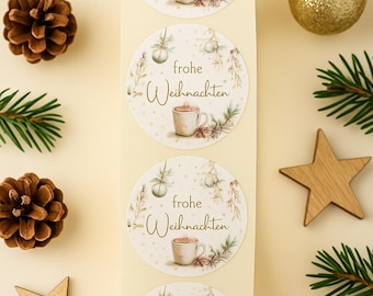 以下が含まれることがあります： 「frohe Weihnachten」の文字とコーヒーカップのイラストが描かれた丸いステッカーのシート。ステッカーは、お祝いの植物のイラストで飾られています。画像には、松ぼっくり、木の星、金のオーナメントも含まれています。