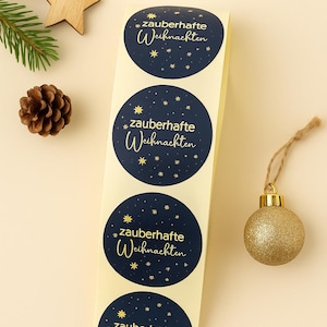 May include: A strip of four navy blue circular stickers with the text "zauberhafte Weihnachten" in gold script, surrounded by gold stars. A gold glitter ornament, a wooden star, and a pine cone are also visible.