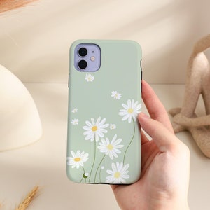 May include: A light green phone case with a white daisy pattern. The case has a camera cutout and a raised lip around the edges.