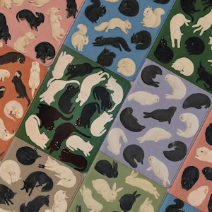 May include: A collection of rectangular mats featuring repeating patterns of animals including cats, dogs, squirrels, seals, and rabbits in black and white against various coloured backgrounds like pink, blue, green, and purple.