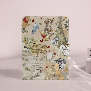 Può includere: Una custodia beige con illustrazioni di Winnie the Pooh e amici. Il design include un cartello di benvenuto per il Bosco dei Cento Acri, api, cuori e il testo "As soon as I saw you knew a grand adventure was about to happen."