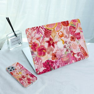 Könnte beinhalten: Ein Laptop und eine Handyhülle mit einem rosa Blumendesign, einschließlich Muscheln, Cocktails und Früchten. Der Laptop ist geöffnet und zeigt den Bildschirm. Die Handyhülle befindet sich neben dem Laptop. Eine klare Glasflasche mit schwarzen Stäbchen im Hintergrund.