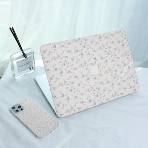 May include: A white laptop, a white iPhone, and a clear glass bottle with a black label that says "Mose Fragrance". All three items have a blue and white floral pattern.