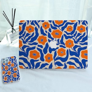 Può includere: Una custodia rigida per laptop e una cover per smartphone abbinata con un motivo ripetuto di fiori arancioni con centri blu e foglie ondulate blu scuro su sfondo crema. La custodia per laptop presenta un ritaglio centrale.
