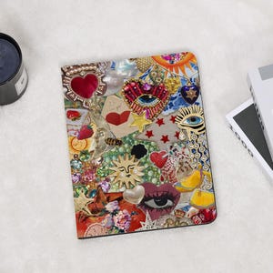 Puede incluir: Un diario decorativo con un diseño de collage. La portada presenta una mezcla de corazones, estrellas y motivos de ojos, con una paleta de colores vibrantes que incluye rojo, dorado y azul. El texto "P.S. I love you!" es visible.