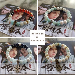 May include: Four beaded bracelets with a clover charm are displayed. The bracelets feature various color combinations, including red, black, white, and blue beads. The text "MO DAO ZU SHI BRACELETS" is visible.